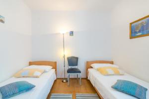 two beds in a room with a blue chair at Apartment Arbanija 7543a in Trogir