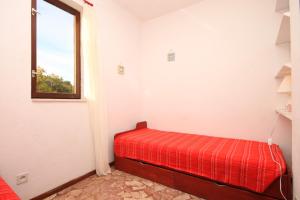 a red bed in a room with a window at Seaside holiday house Razanj, Rogoznica - 7514 in Rogoznica
