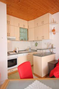 a kitchen with white cabinets and a red chair at Apartments with a parking space Vela Luka, Korcula - 7551 in Vela Luka