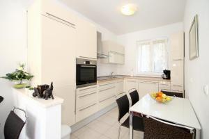 a kitchen with white cabinets and a table with a bowl of fruit at Apartments with a parking space Split - 7569 in Split