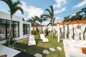 a backyard with two white chairs and a pergola at Villa Lamer Canggu in Canggu