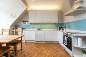 a kitchen with white cabinets and a wooden table at Caddyshacks Gullane, 4 bedroom, 4 bath, Golf, Beach in Gullane