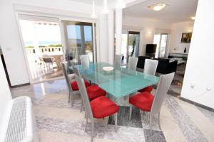 uma sala de jantar com uma mesa de vidro e cadeiras em Family friendly apartments with a swimming pool Rogoznica - 7557 em Rogoznica