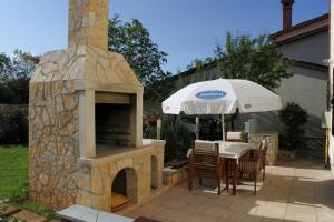 a stone pizza oven with a table and chairs and an umbrella at Apartments with a parking space Peroj, Fazana - 7516 in Vodnjan