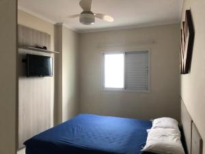 Un dormitorio con una cama azul y una ventana. en Apartamento beira mar - Mongaguá, en Mongaguá