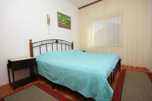 a bedroom with a bed with a blue blanket and a window at Holiday apartments Pjescana Uvala, Pula - 7652 in Pula