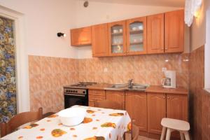 a kitchen with a table and a sink and a stove at Holiday apartments Pjescana Uvala, Pula - 7652 in Pula