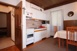 uma pequena cozinha com armários brancos e uma mesa e uma mesa; em Apartments with a parking space Ravni, Labin - 7613 em Ravni