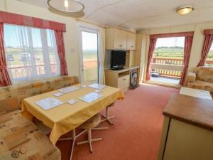 a dining room with a table and a television at Gorphwysfa Caravan in Cemaes Bay