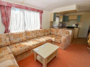 sala de estar con sofá y mesa en Gorphwysfa Caravan en Cemaes Bay