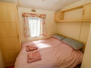 Cama pequeña en habitación pequeña con ventana en Gorphwysfa Caravan en Cemaes Bay