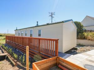 uma casa com um deque de madeira ao lado de um edifício em Gorphwysfa Caravan em Cemaes Bay