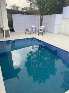 a swimming pool with two chairs and a table at Diyar Villas Puncak M6/14 in Puncak