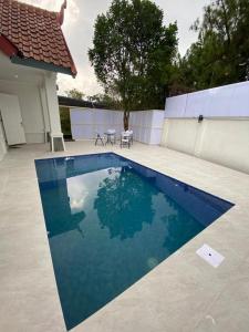 - une piscine d'eau bleue à côté d'une maison dans l'établissement Diyar Villas Puncak M6/14, à Puncak