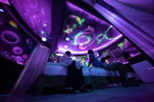 un groupe de personnes assises dans une pièce dotée d'un plafond violet dans l'établissement Buzz Resort, à Onna