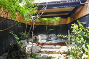 um jardim com pedras e um lago em frente a uma cerca em Ryokan Yayanoyu em Ueki