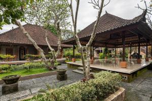 un pavillon dans un jardin avec des arbres et des plantes dans l'établissement Puri Saraswati Dijiwa Ubud, à Ubud
