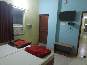 a room with two beds and a window and a television at Rama Guest House in Bodh Gaya