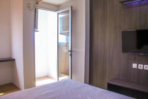 1 dormitorio con 1 cama y puerta corredera de cristal en RedLiving Apartemen Gunung Putri Square - Abidin Room Tower Pinus, en Parungtandjung
