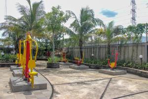 un patio con palmeras y un parque infantil con equipamiento colorido. en RedLiving Apartemen Gunung Putri Square - Abidin Room Tower Pinus, en Parungtandjung