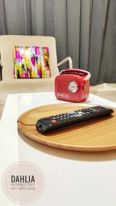 a red radio and a remote control on a table at Dahlia Homestay Putrajaya in Putrajaya
