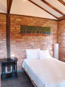 ein Schlafzimmer mit einem Bett und einer Ziegelwand in der Unterkunft Cabaña lagovilla in Villa de Leyva