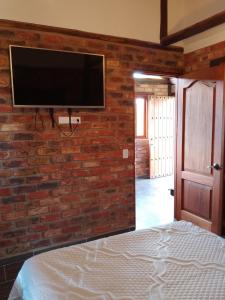 a bedroom with a brick wall with a flat screen tv at Cabaña lagovilla in Villa de Leyva