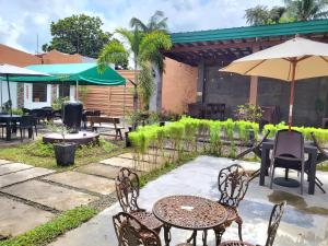a patio with tables and chairs and an umbrella at North Tourist Inn in Bacolod