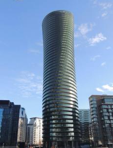 a tall glass building in the middle of a city at Luxury Canary Wharf 2 Bed Apartment With Panoramic Views in London