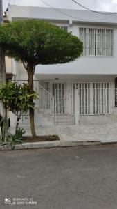 a white building with a tree in front of it at Agradable casa para una excelente estadía. in Palmira
