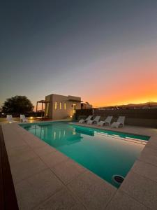 a swimming pool with chairs and a sunset in the background at Tierras del Norte in Salta