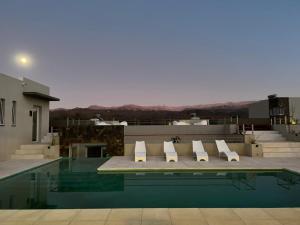 une piscine avec des chaises longues blanches sur le toit dans l'établissement Tierras del Norte, à Salta