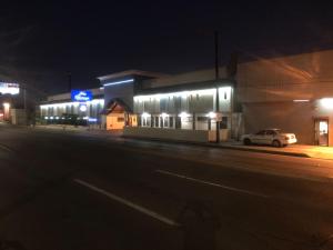 Ein Auto, das nachts vor einem Gebäude geparkt ist in der Unterkunft Hotel Boulevard Mexicali in Mexicali
