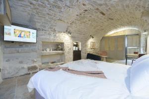 um quarto com uma cama branca numa parede de pedra em Les Confidentielles em Balaruc-le-Vieux