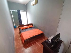 哲帕拉的住宿－Nathaniela Homestay，一间卧室配有带橙色床单的床和窗户。