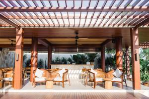 a wooden pergola with chairs and tables on a patio at Amarta Beach Retreat by Nakula in Tabanan