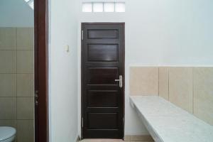 La salle de bains est pourvue d'une porte noire et de toilettes. dans l'établissement RedDoorz Syariah @ Jalan Tingang Palangkaraya, à Palangka Raya