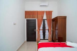 um quarto com uma cama e uma porta com cortinas em RedDoorz Syariah @ Jalan Tingang Palangkaraya em Palangkaraya