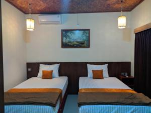 two beds sitting in a room with two lamps at Indah Nusantara in Banyuwangi