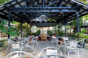 um grupo de mesas e cadeiras sob uma pérgola em Sahabat Pantai Guest House Mitra RedDoorz em Tanjungbinga