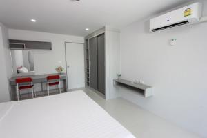 a white kitchen with red chairs and a counter at Matasiri Residence in Ban Bang Phang