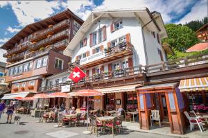um edifício com uma bandeira canadiana e mesas e cadeiras em Eiger Guesthouse em Mürren