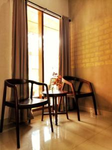 Duas cadeiras e uma mesa num quarto com uma janela em OASIS HOTEL em Ampana