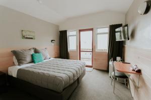 a bedroom with a bed and a desk and window at Waitomo Village Chalets home of Kiwipaka in Waitomo Caves