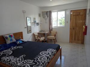 a bedroom with a bed and a table and a window at Kathleens Vacation Place in Moalboal