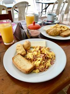 un plato de desayuno con tostadas, pan y zumo de naranja en Hotel Manantial, en Buga