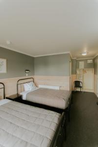 a bedroom with two beds and a chair in it at Waitomo Village Chalets home of Kiwipaka in Waitomo Caves