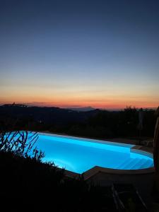 a swimming pool with a sunset in the background at Il Picchio Verde in SantʼAngelo in Pontano