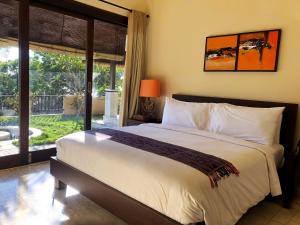 a bedroom with a large bed and a large window at Lombok Sunset Bay Resort in Sekotong