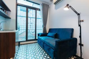 a living room with a blue couch and a large window at Hanoi Old Quarter in Hanoi